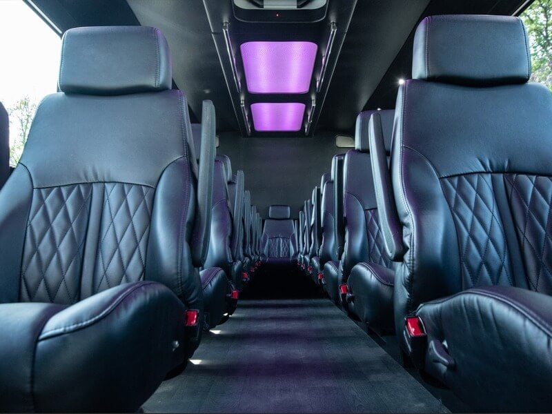 20 passenger shuttle bus interior with black leather seats and purple ceiling lighting